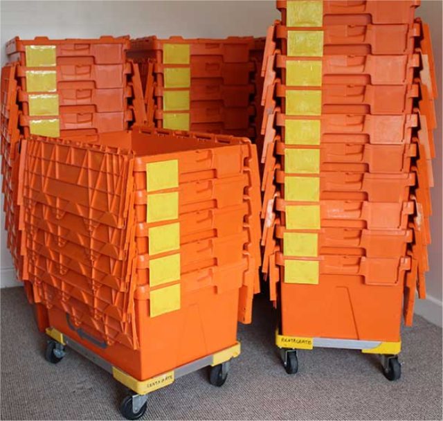 Stacks of orange reusable moving crates with yellow labels